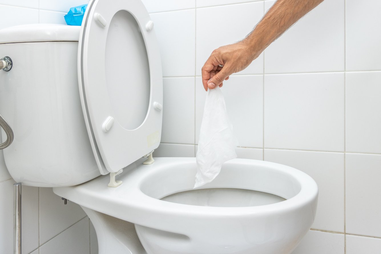 Hand Throwing Wet Wipe into Toilet Bowl